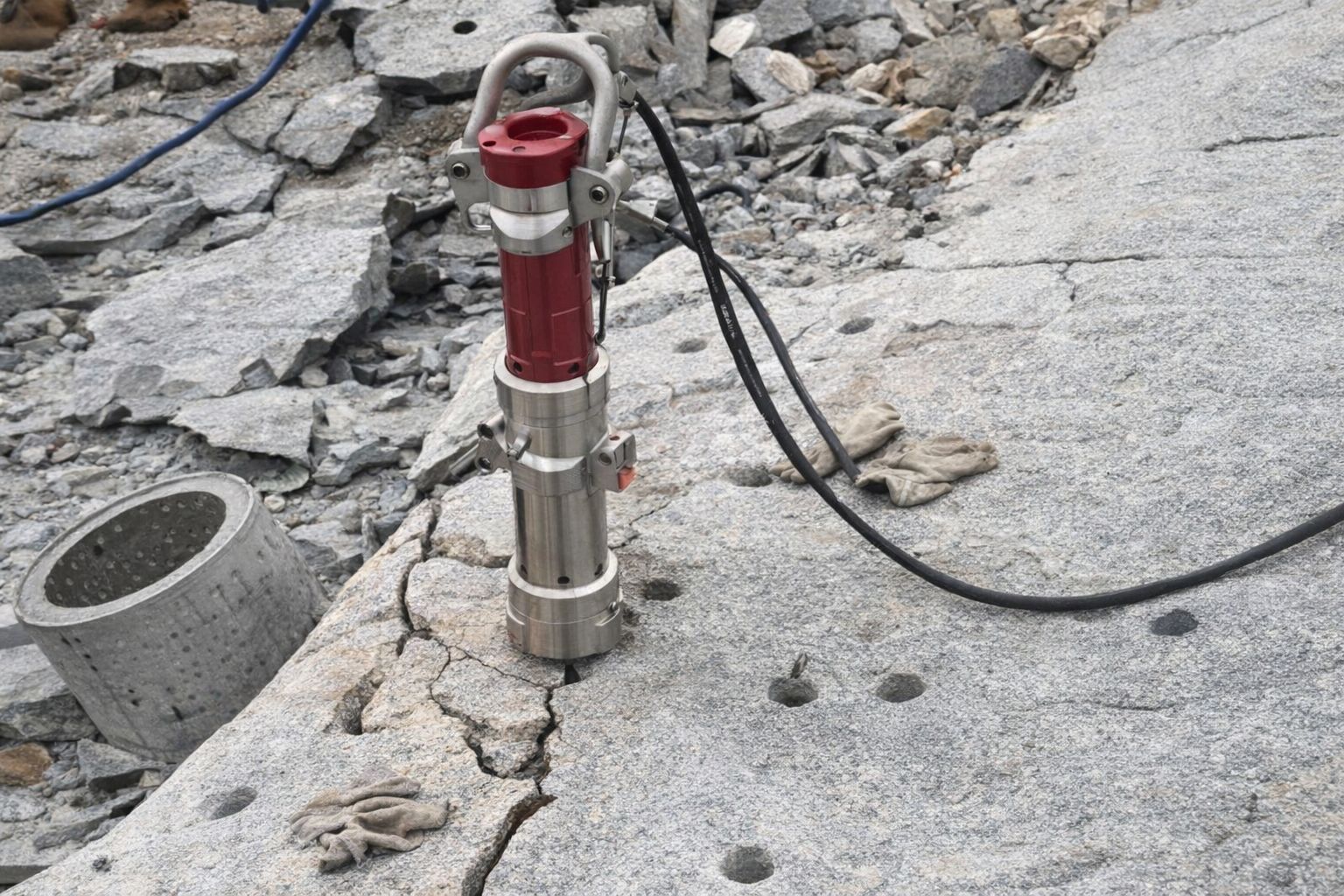 En hydraulisk stenspräckare monterad i ett borrhål i gråsten.