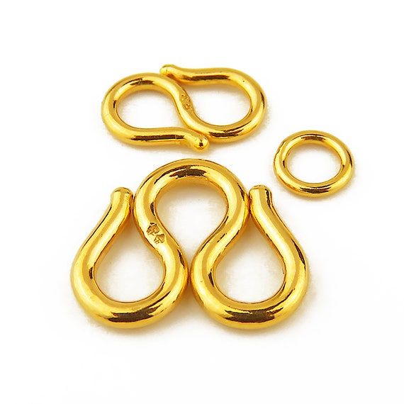 Guldfärgade S-lås och ring för bismarck armband på vit bakgrund.